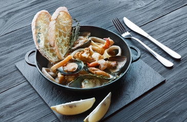 Seafood Stew in Saucepan on dark wood background