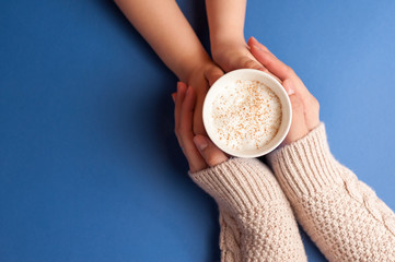 Two pairs of hands holding coffee with milk froth and cinnamon on top