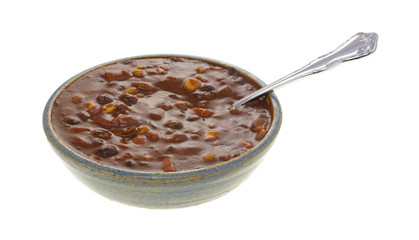 Vegetable chili in an old bowl with spoon isolated on a white background.