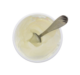 Sour cream in plastic container with a spoon top view isolated on a white background.