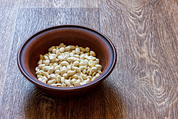 Peanuts in a clay plate on a wooden table