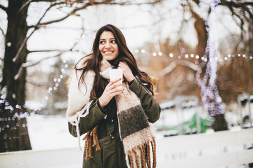 Happy woman with a cup of hot drink on  cold winter outdoors