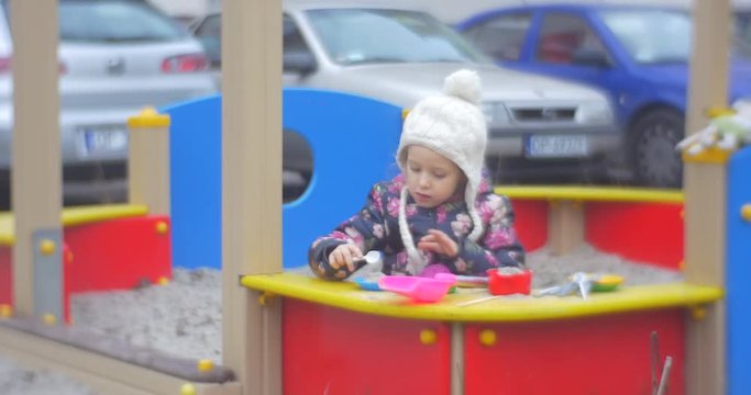 Girl Playing in the Sandbox Making Cakes