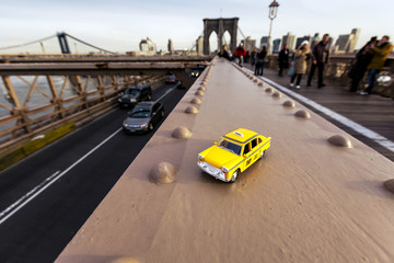 Model of a classic yellow taxi on a steel beam on Brooklyn Bridge.