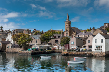 Orkneys, Scotland - June 5, 2012: View on the old cluttered docks with parish church towering over...