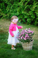 little girl stands near a basket of flowers