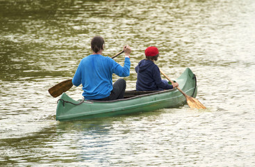 Family on canoe tour. Father and child paddling in kayak in a lake on a sunny day. 