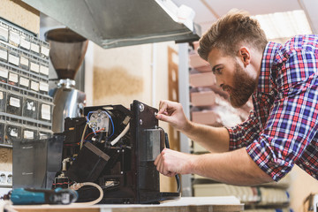 Serious man repairing broken coffee machine
