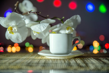 cup of coffee on a bamboo napkin on a background of white orchids 