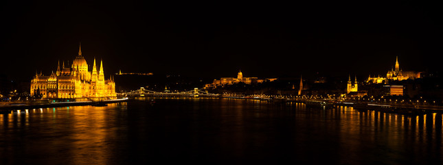 Fototapeta na wymiar Panoramic night view on Hungarian Parliament Building located at the bank of the Dunabe river with famous Chain Bridge connecting Buda and Pest in Budapest, Hungary