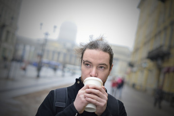 The man in the black coat drinking coffee in the street of St. Petersburg in the glass.