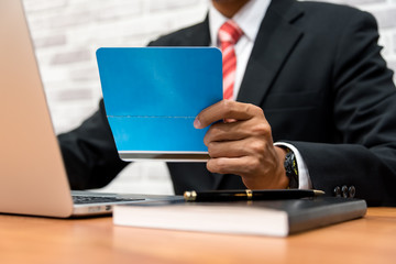 businessman holding account book and using laptop in his office