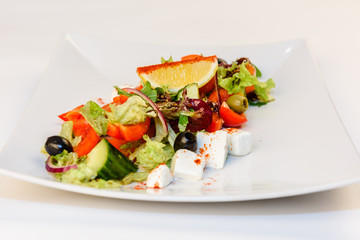 Greek salad close up with feta cheese, tomatoes, olives and green leafs