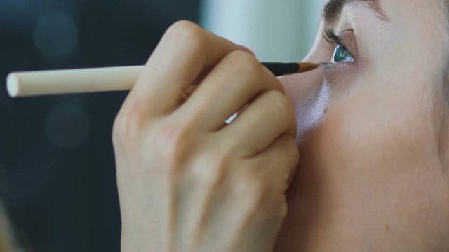 Slow motion of young make-up artist makes a girl beautiful makeup closeup before an important event
