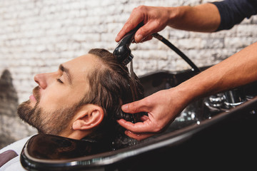 Professional barber undergoing hairwash at salon