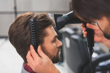 Barber using hairdryer at beauty salon