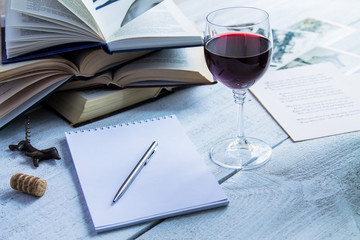 Glass of red wine and a book on a white wooden background