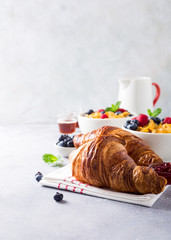 Croissants, corn flakes and berries on light gray background. Copy space. Healthy breakfast concept.