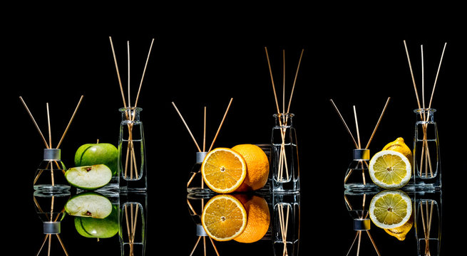 Air fresheners in a glass jars with sticks and lemon, green apple and orange with reflection isolated on a black background. Big large size. 
