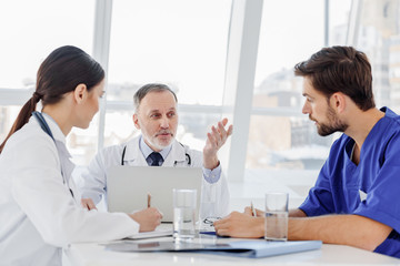 Mature general practitioner explaining something to interns