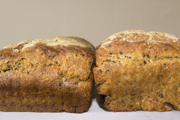Two crusts of homemade bread . The Polish kitchen. Brown bread made from rye on a grey napkin . Light background .