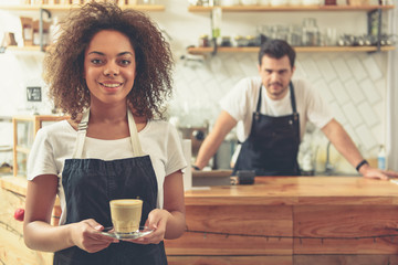 Waitress holding cup of delicious latte in hands