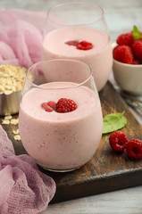 Raspberry and banana smoothie with oatmeal on the rustic wooden table, selective focus, vertical, copy space