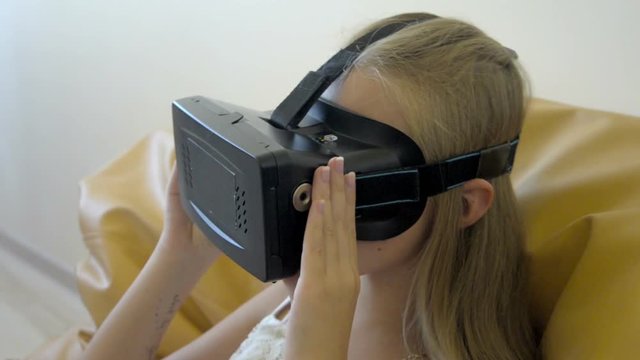 Teenager girl going up and down with her head in vertual glasses