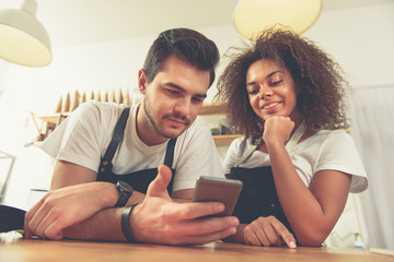 Happy couple looking at mobile in cafe