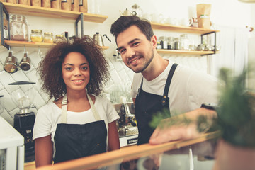 Laughing baristas standing in kitchen at stand
