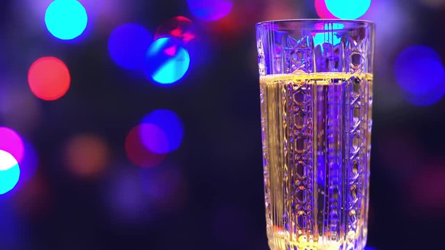 glass of sparkling wine (champagne) on a background of twinkling lights bokeh.