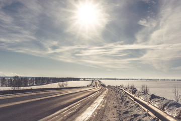 Asphalt road in snowy winter on beautiful frosty sunny day. Retro toned picture