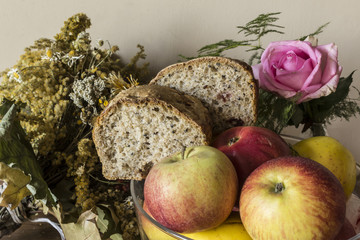 Homemade bread with cranberries and other additives. Polish cuisine. Still life with rye bread, apples, dried flowers and rose..