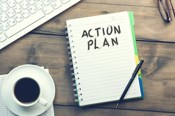 action plan text on notebook with keyboard and coffee on table