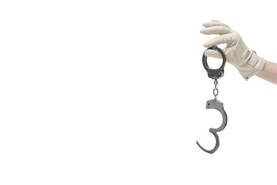 Mit Lederhandschuh bekleidete Damenhand h&auml;lt Handschellen 