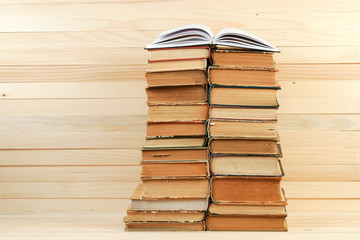 Fototapeta premium Open book, stack of hardback books on wooden table.