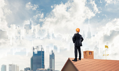 Engineer man standing on roof and looking away. Mixed media