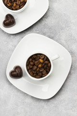 White cups for espresso filled with coffee beans and chocolate i