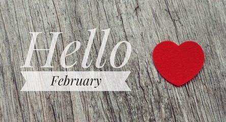 Hello February words on red heart and wooden background