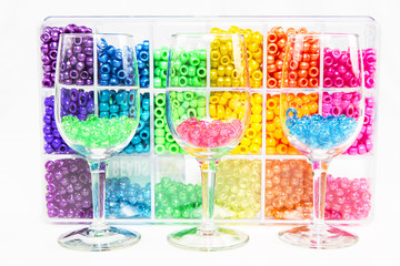 High Key image of plastic beads in wine glasses using primary colors juxtaposed against bulk beads