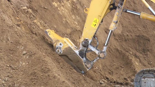 Excavator digs the ground, the bucket close up
