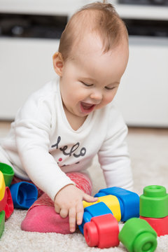 Nine months old baby girl sitting on the floor and playing with
