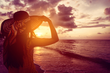 Touristin am Meer sieht sich Sonnenuntergang an tropischem Strand an