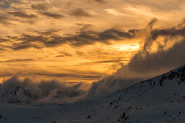 Vibrant orange sunset over snowy mountains