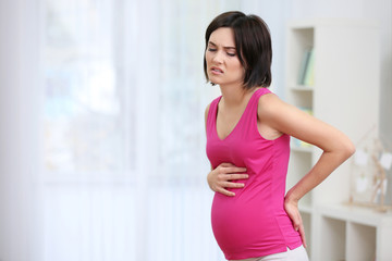 Young pregnant woman suffering from backache at home