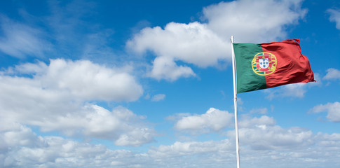 Portugiesische Flagge vor Himmel mit weissen Wolken