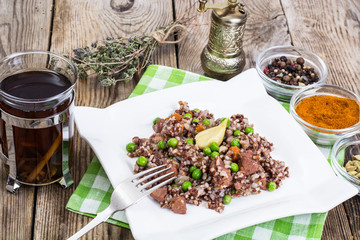 Boiled red rice with vegetables and slices of chicken on a woode