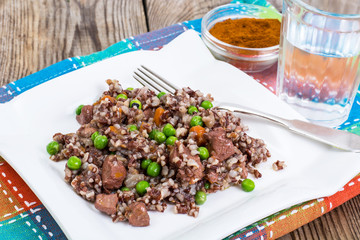 Boiled red rice with vegetables and slices of chicken on a woode