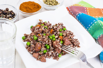 Boiled red rice with vegetables and slices of chicken on a woode
