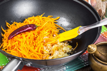 Grated pumpkin with chopped onion in a frying pan
